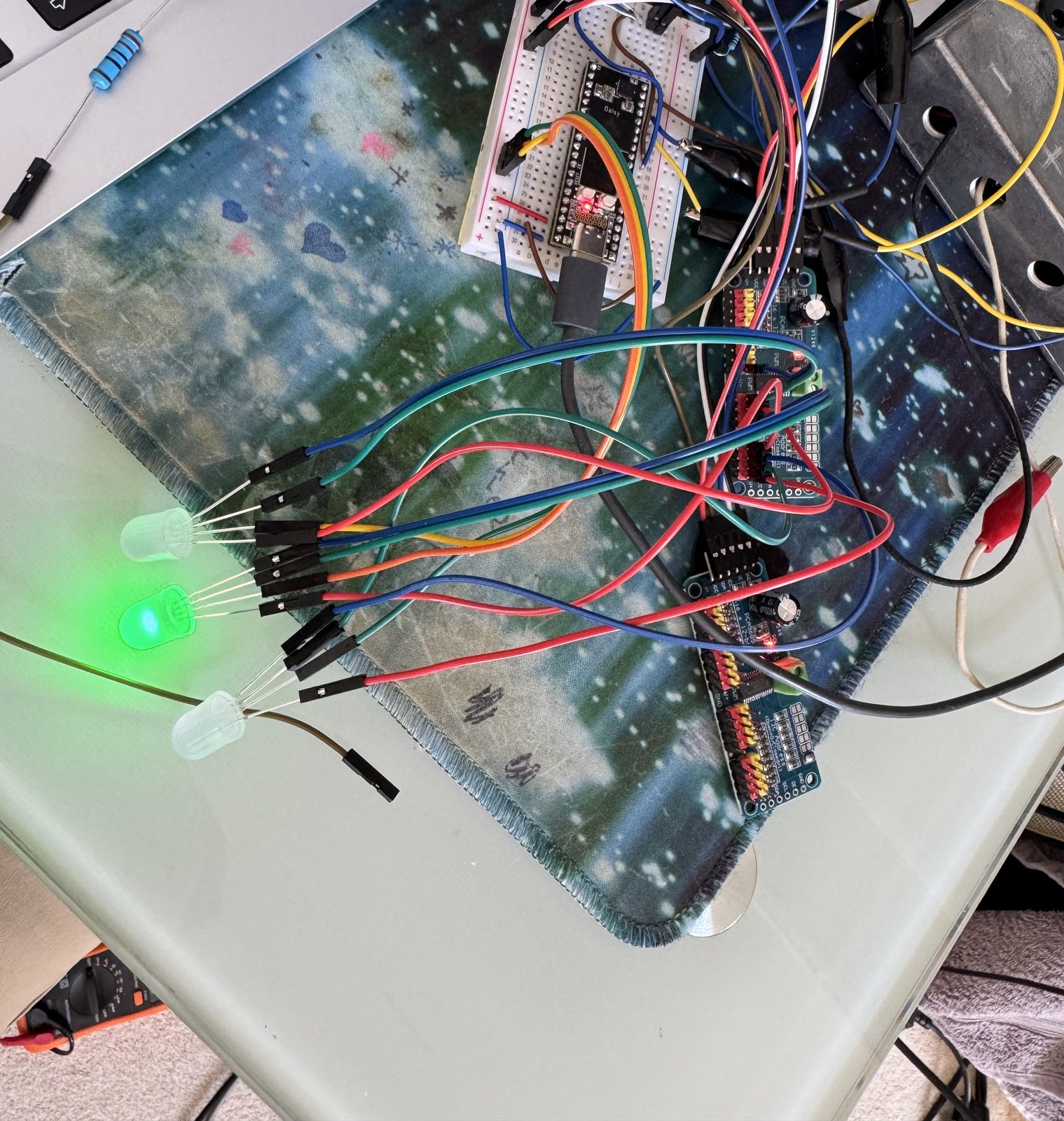 A Daisy Seed on a small breadboard beside a laptop, wired to two blue LED driver boards and three loose lights, one of them lit green