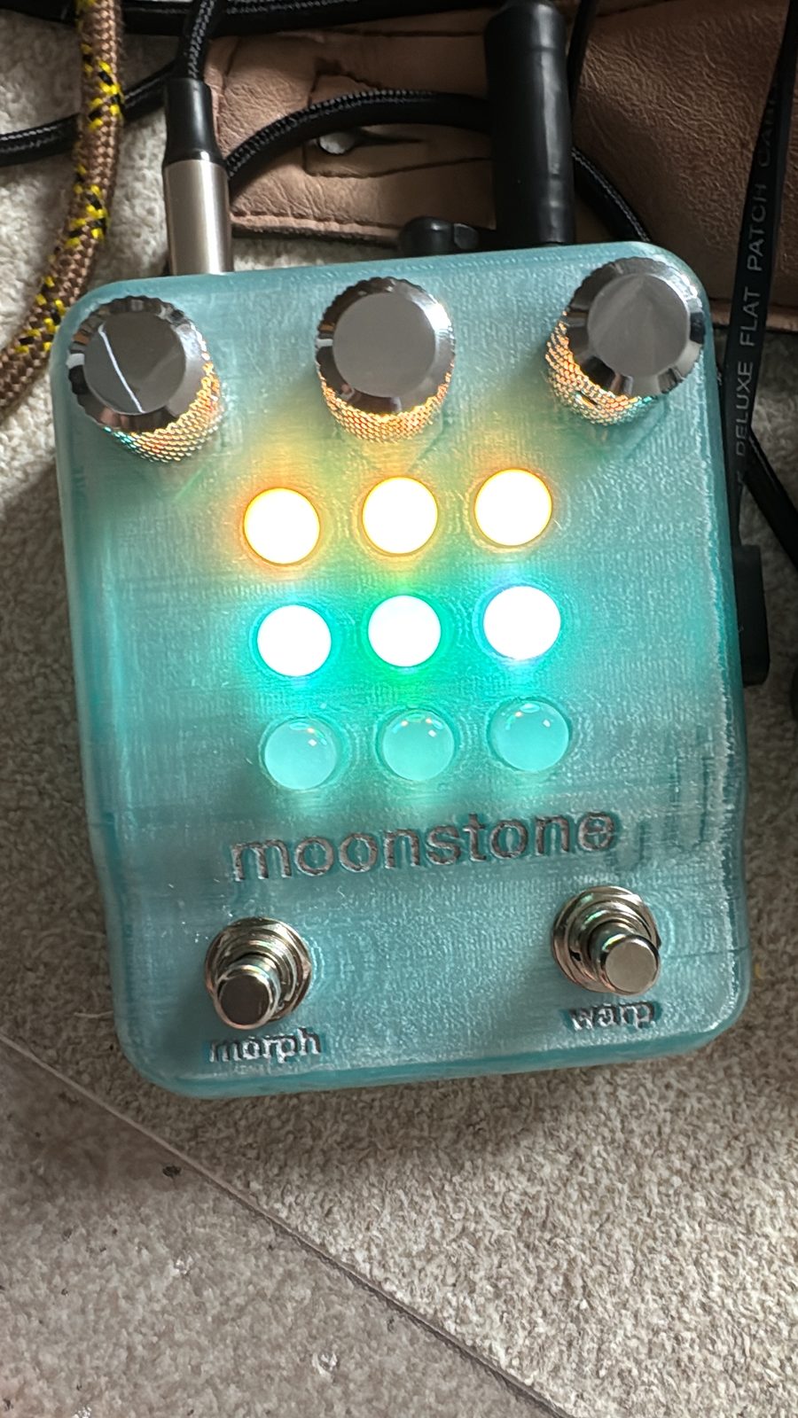 A pale teal moonstone with chrome knobs, its top row of lights orange and its middle row green